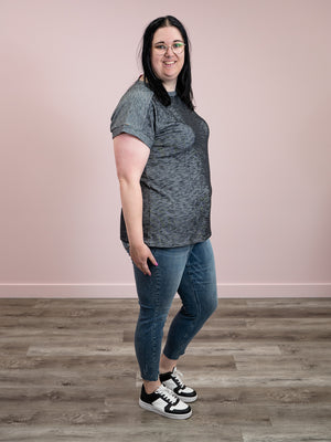 Side view of Michelle wearing a charcoal short sleeve top with blue jeans and black and white sneakers